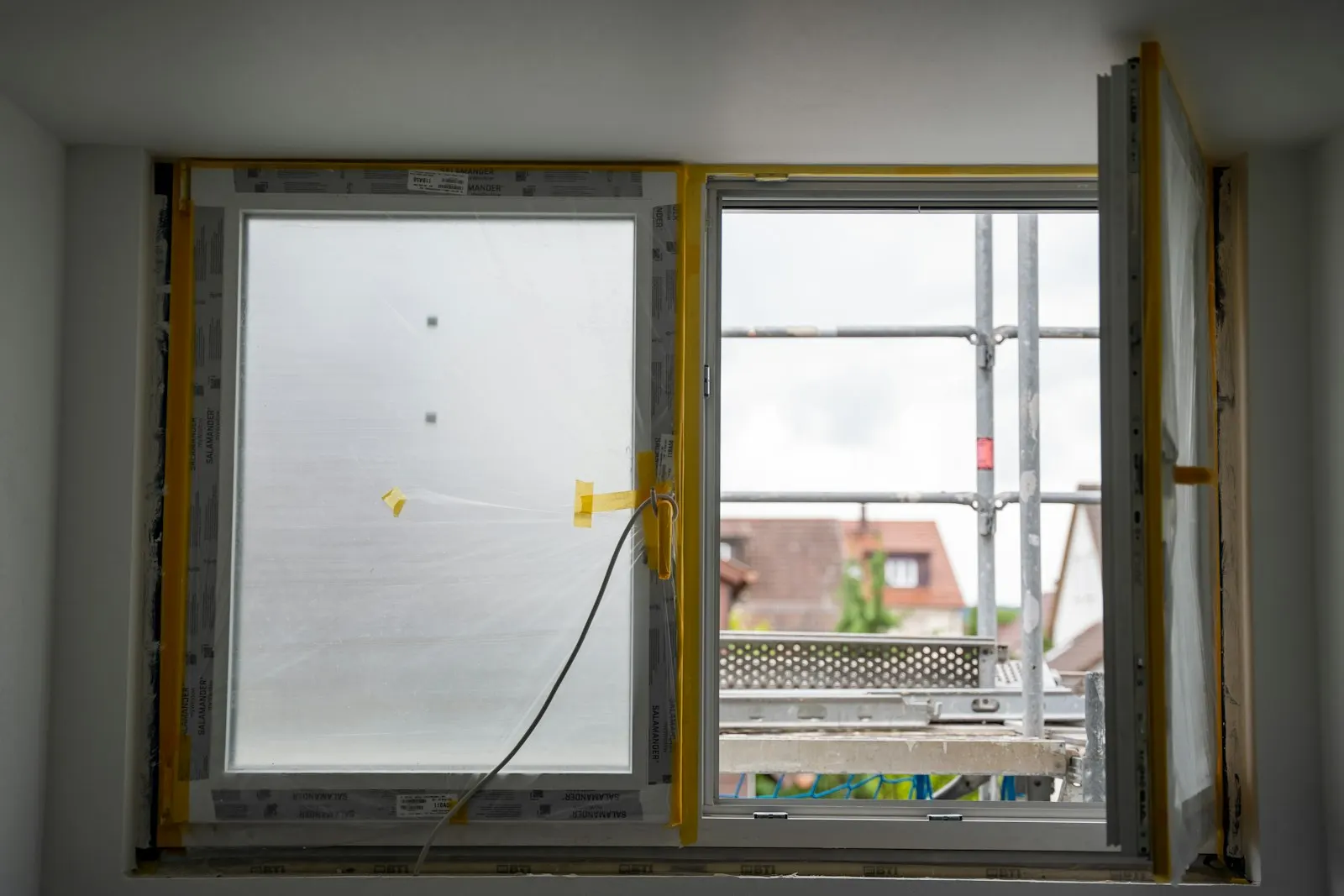 Fenster mit Schutzfolie und Gerüst an einem Gebäude in Deutschland